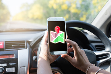 Woman in car holding a smartphone with  checks map to find directions  in her hand. Technology,...