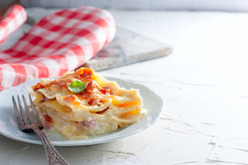 A slice of homemade lasagna with ham and cheese, copy space