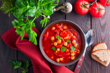 Chickpeas with tomatoes and chorizo on a wooden table, top view