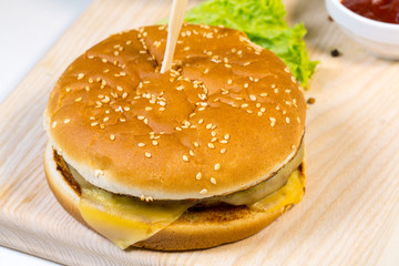 Burger with potatoes on a wooden board in a composition on a table