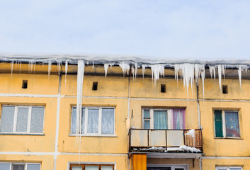 Lcicles and snow on the roof of the house
