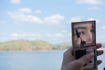 Asian female eye in mirror with blur blue sky background