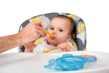 The father feeds with porridge of the one-year-old kid, isolated on the white