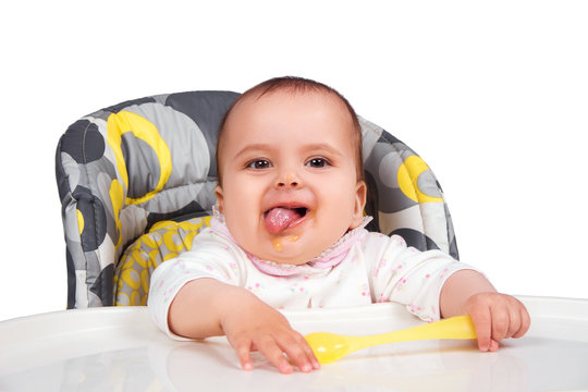 happy baby child sitting in chair with a spoon