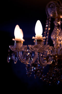 A burning light bulb on a crystal chandelier on a dark background