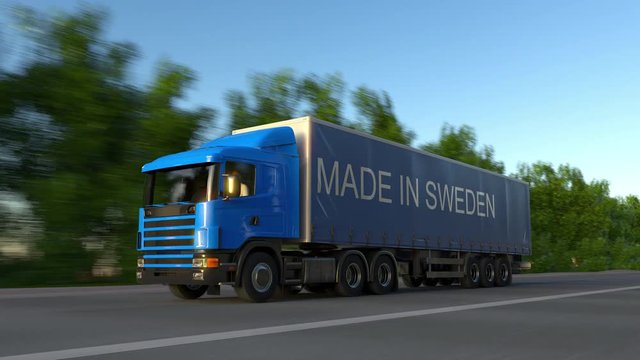 Speeding freight semi truck with MADE IN SWEDEN caption on the trailer. Road cargo transportation. Seamless loop 4K clip