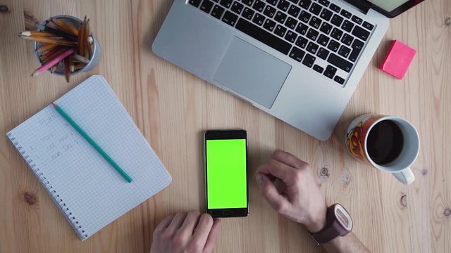 Top view hands using mobile phone touchscreen multi touch gestures green screen wooden desk