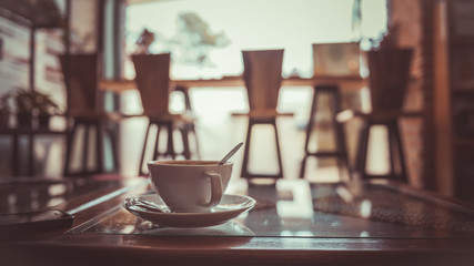 White cup of hot coffee on table in cafe. 