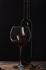 wineglass with bottle, corkscrew on wooden table with sackcloth napkin