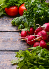 Harvest Vegetables: sadishes, tomatoes, cucumbers, parsley,  onion, arugula at the basket on the wooden background