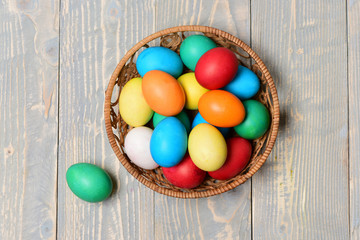 Obraz na płótnie Canvas colorful painted eggs in basket on wooden background, easter holiday