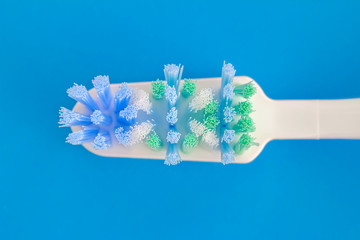 Toothbrush head on blue background, top view, macro image.