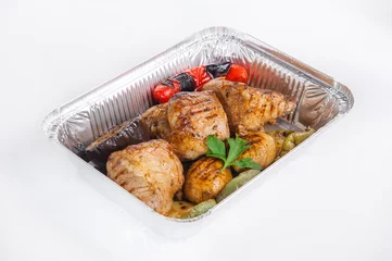 Fototapeten Close up Healthy restaurant food delivery in foil box. Grilled meat steak and vegetables. Meals take away, selective focus. Isolated on the white background. © okrasiuk
