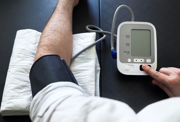 man self-monitoring of blood pressure with a tensiometer / Hypertensive patient performing a blood pressure auto test