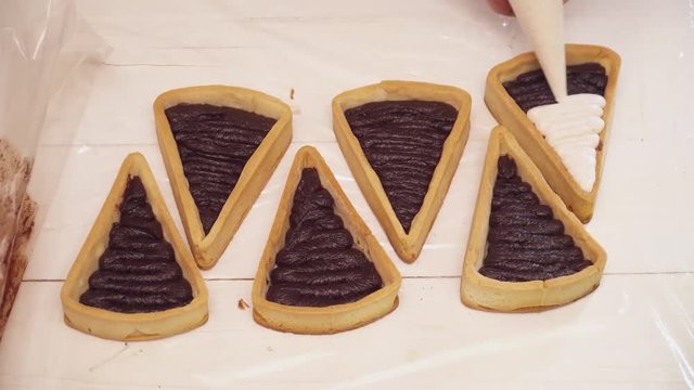 Adding cream to the small tarts with chokolate