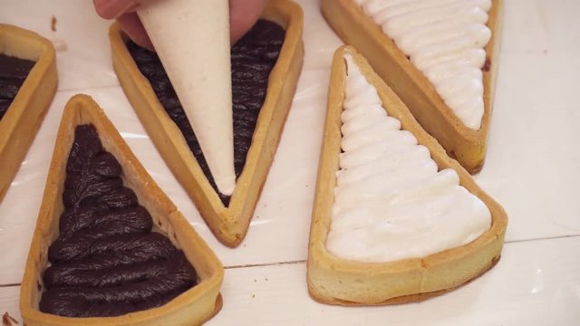 Adding cream to the small tarts with chokolate closeup