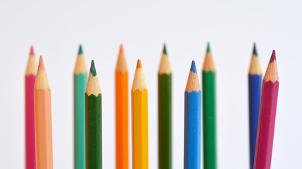 Colored pencils in a row in front of a white background