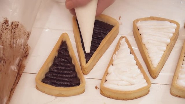 Adding white cream to the small tarts with chokolate