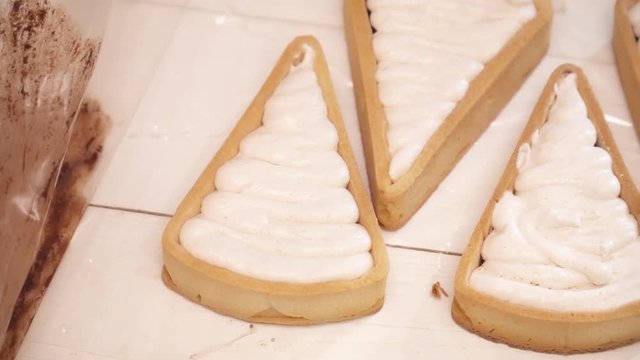 Adding white cream to the small tarts with chokolate closeup