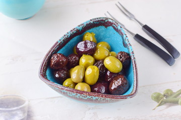 Green and black olives in olive oil in a traditional Greek bowl. Mediterranean lifestyle