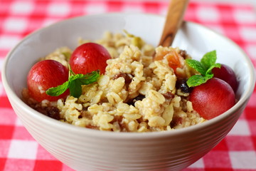 Healthy Oatmeal recipes. Porridge in a ceramic bowl with grapes on a red background