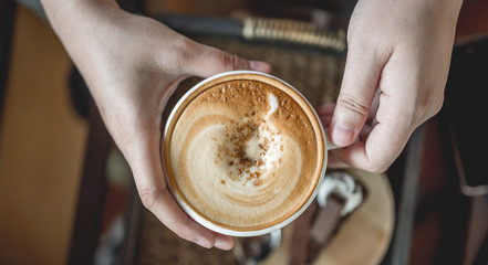 Fototapeta na wymiar Hands holding on hot latte coffee mug.