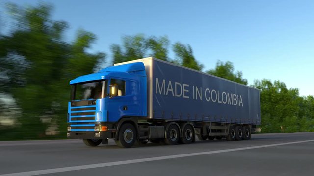 Speeding freight semi truck with MADE IN COLOMBIA caption on the trailer. Road cargo transportation. Seamless loop 4K clip