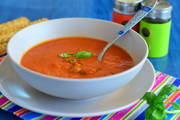 Tomato soup with mussels in a blue bowl on a blue background with bread sticks. Healthy eating concept