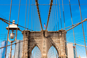 Naklejka premium american flag flying on an arch of Brooklyn Bridge, New York