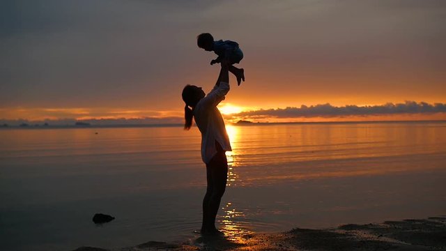the girl with the child go for walks and play on the beach at sunset time