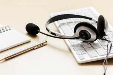 Office desk with headset and keyboard brown background