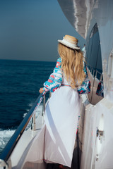 Obraz premium Girl in a long dress and hat on a yacht