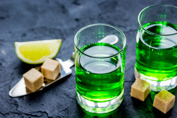 absinthe with sugar cubes in spoon on dark background