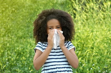 Seasonal allergy. Little African-American girl with tissue outdoor