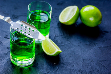 absinthe shots with lime slices on dark table background space for text