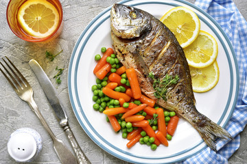 Baked dorado or sea bream with spring vegetables.Top view.