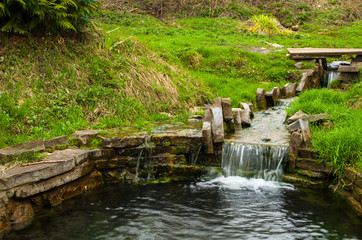 Fototapeta na wymiar Wellspring natural water flowing through a stone trough