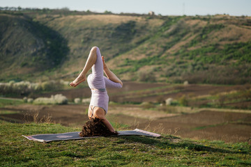 Young woman doing complex Yoga exercise on a rock