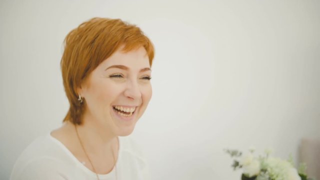 An attractive caucasian adult woman smiles, talks and laughs at the camera