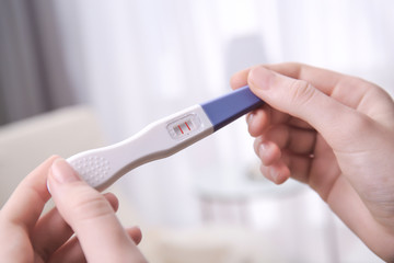 Pregnancy test in female hands on blurred background