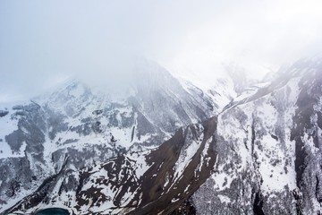 Горный пейзаж, красивый вид на высокие снежные склоны, небо в белых облаках. Горы и природа Северного Кавказа, Грузия