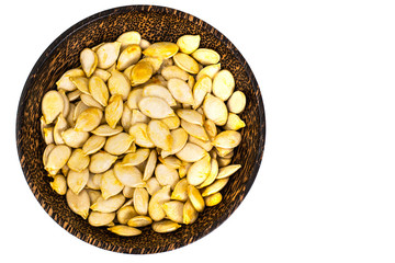 Dry uncooked pumpkin seeds in wooden bowl