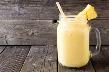 Fotobehang Milkshake Pineapple smoothie in a mason jar, against a rustic wooden background