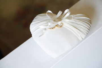 fedi d'oro dentro cuscinetto bianco a forma di cuore