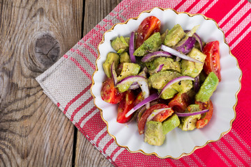 Salad with avocado and tomatoes on wooden background