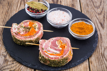 Roll of pork with spices for grilling on black stone