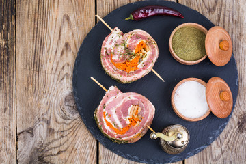 Roll of pork with spices for grilling on black stone