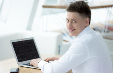 Fototapeta premium Stylish middle-aged businessman looking at camera with toothy smile while working on project in cozy small cafe, portrait