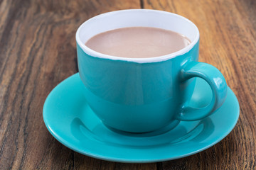 Coffee with milk in blue cup on wooden background