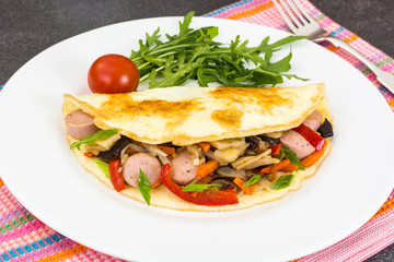 Breakfast omelet with vegetables and sausages